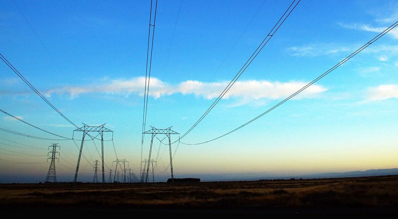Photo of electric utility lines against a blue sky.