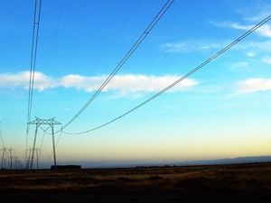Photo of electric utility lines against a blue sky.