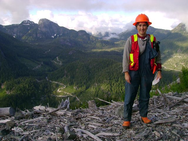 Person standing on a mountain overlooking a forested valley.