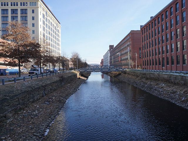 North Canal runs through a section of downtown Lawrence with large buildings on either side.