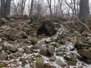 Lime kiln remains in a snowy forest.
