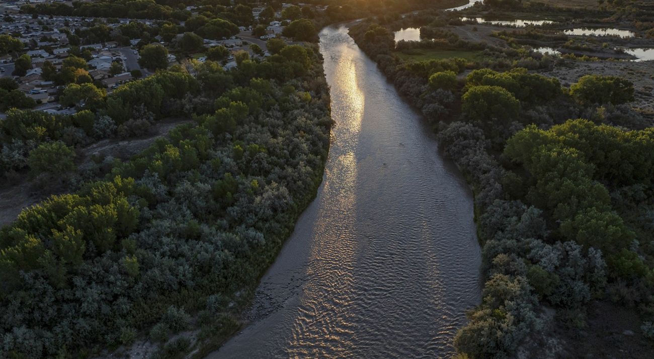 Aerial view of a wide river flowing through a forest.