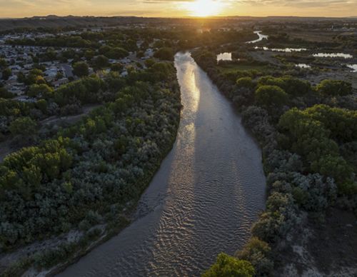 Aerial view of a wide river flowing between a forest.