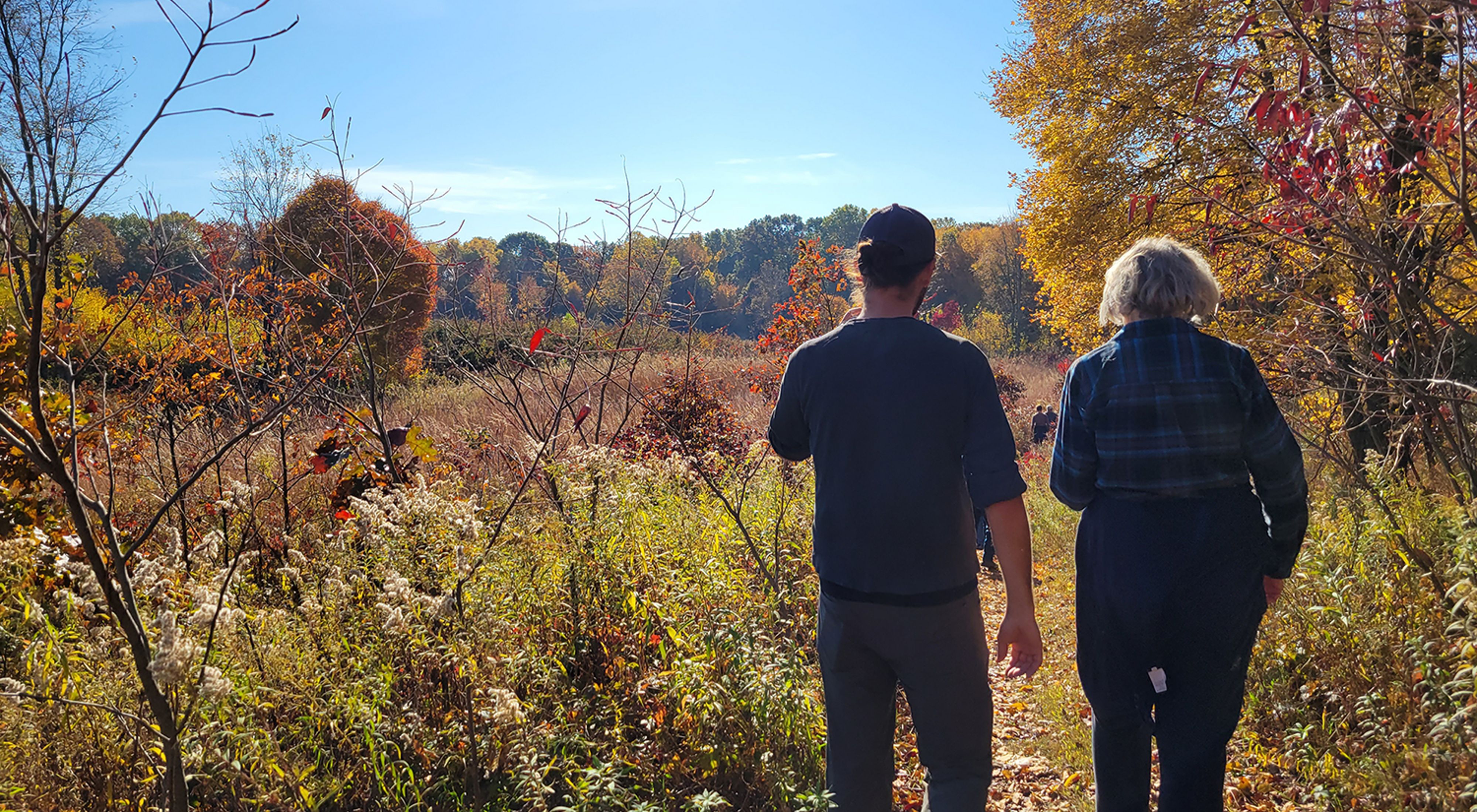 Two people walk along a trail at Paw Paw Prairie Fen Preserve in Michigan in the autumn. 