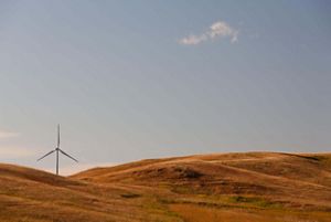 A wind turbine on rolling grasslands.