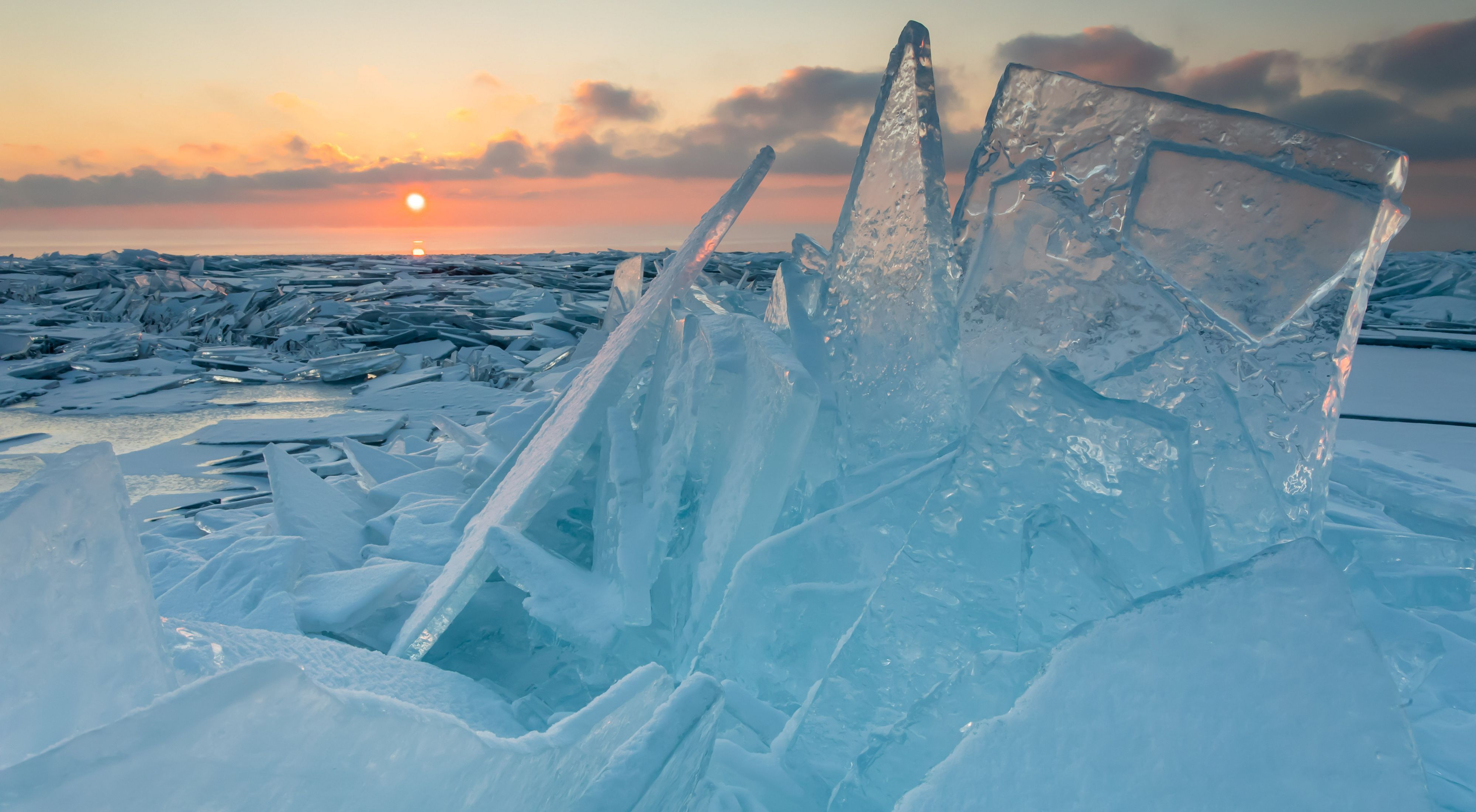 Icy shards on the shore of Lake Superior with a sunset in the background.