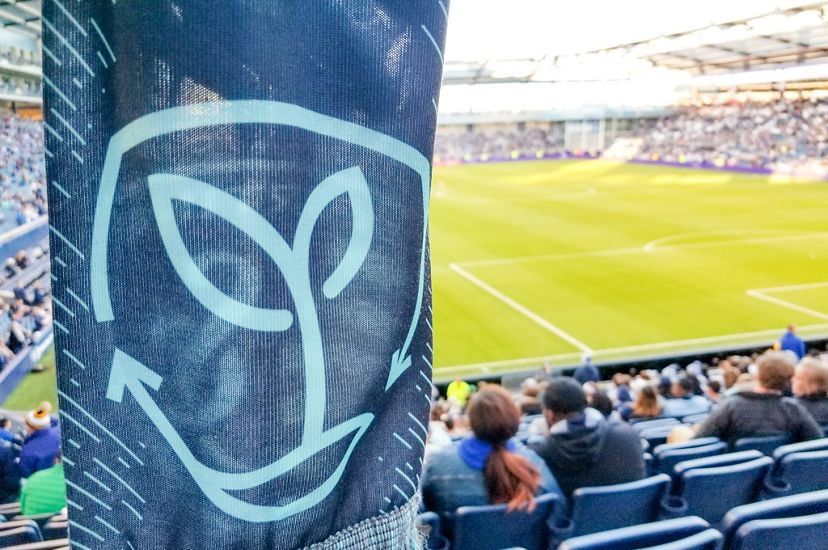 A scarf with the Sporting Sustainability logo with the soccer field in the background.