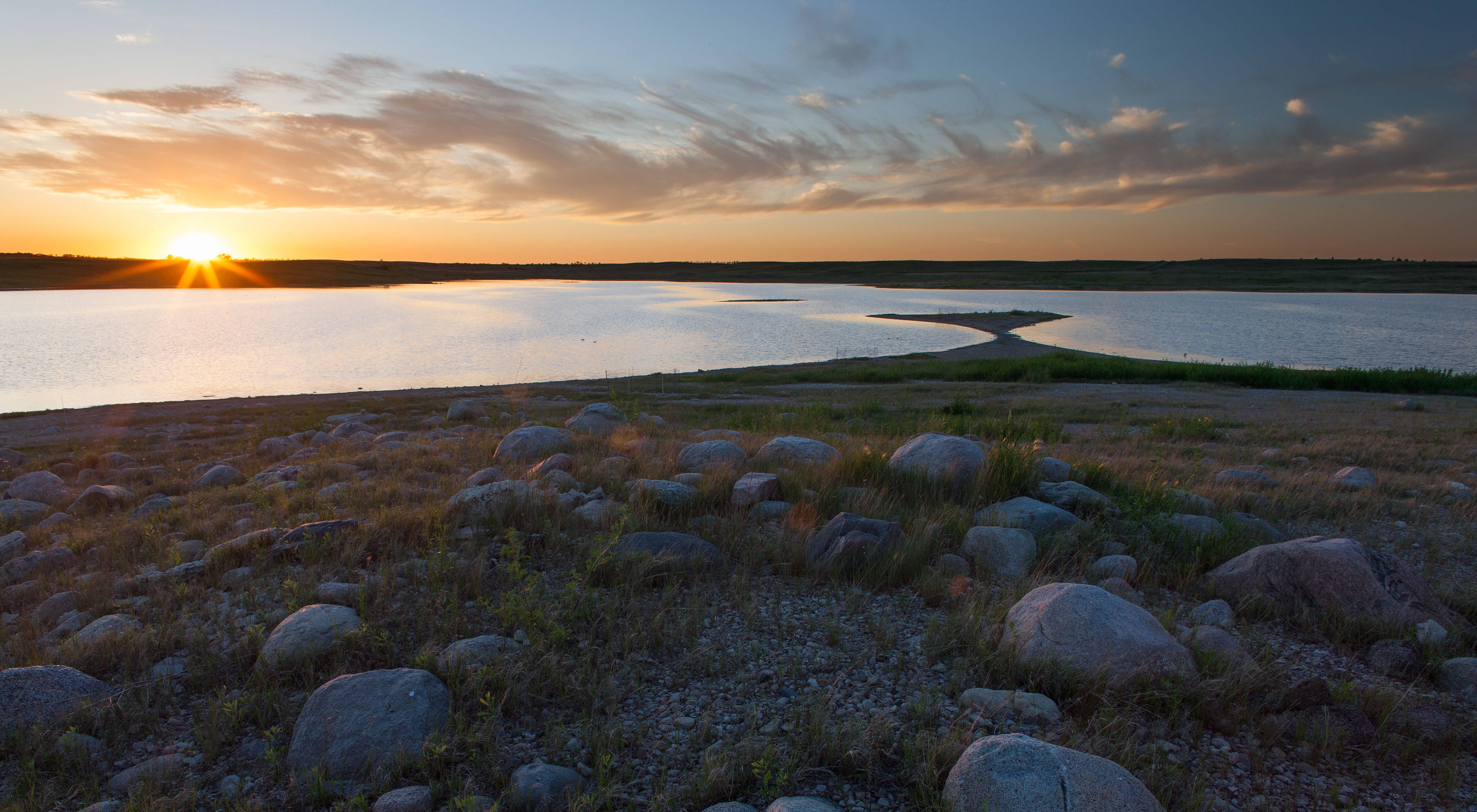 Ponds on a flat prairie strewn with rounded rocks.