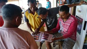 Four men look at a book of fish species.