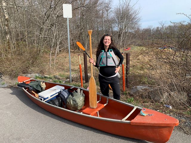 A photo of Josie Marino holding a paddle in front of a canoe. 