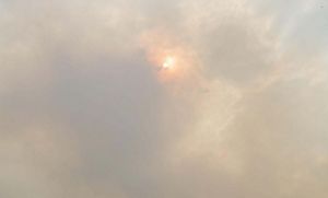 Smoke obscures the orange glow of the sun.