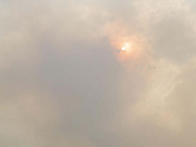 Smoke obscures the orange glow of the sun.