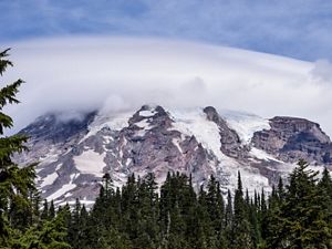 Rocky slopes of Mount Rainier with glaciers and trees.