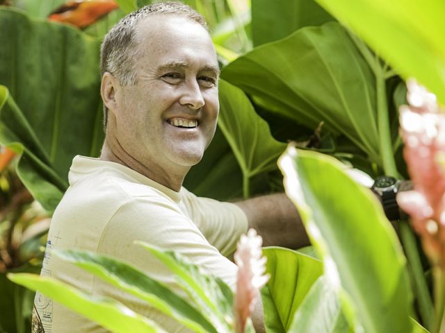 A smiling man standing in the jungle.