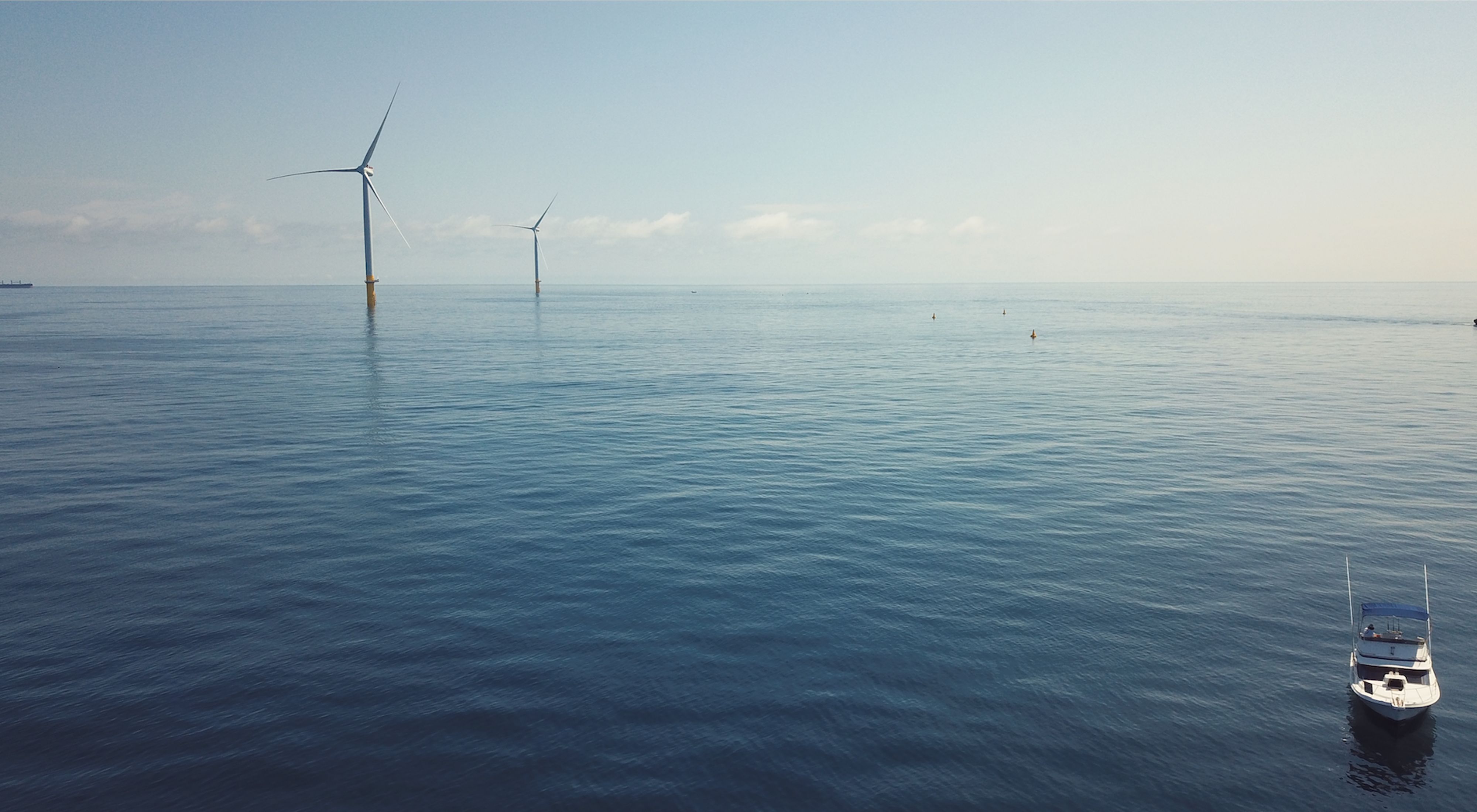 A aerial view of an ocean with wind turbines.