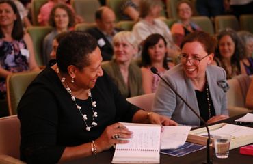 Women at a conference looking at each other smiling and talking.