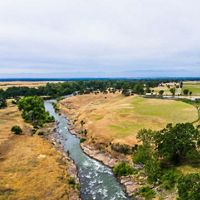 Aerial view of a river cutting through a flat green-and-golden landscape.