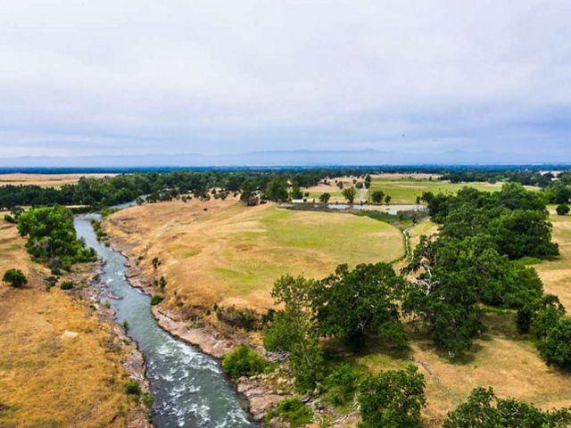 Aerialiew of Nobmann Ranch, with grassy fields, trees, and a stream.