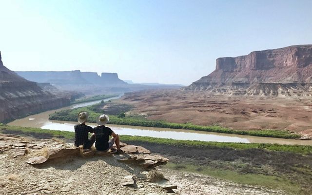 Chad and partner Matthew sit overlooking rocky landscape of Utah's Green River with Canyonlands National Park in distance.