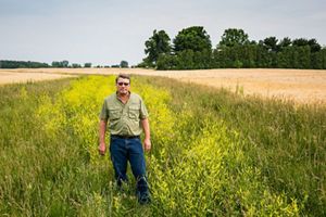 Farmer Les Seiler stands in an agricultural field to show his vegetated drainage ditch.