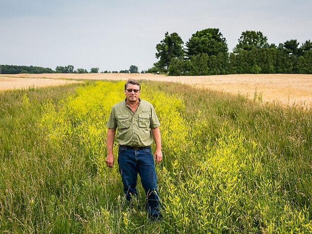 Farmer Les Seiler stands next to two-stage ditch in his agricultural field.