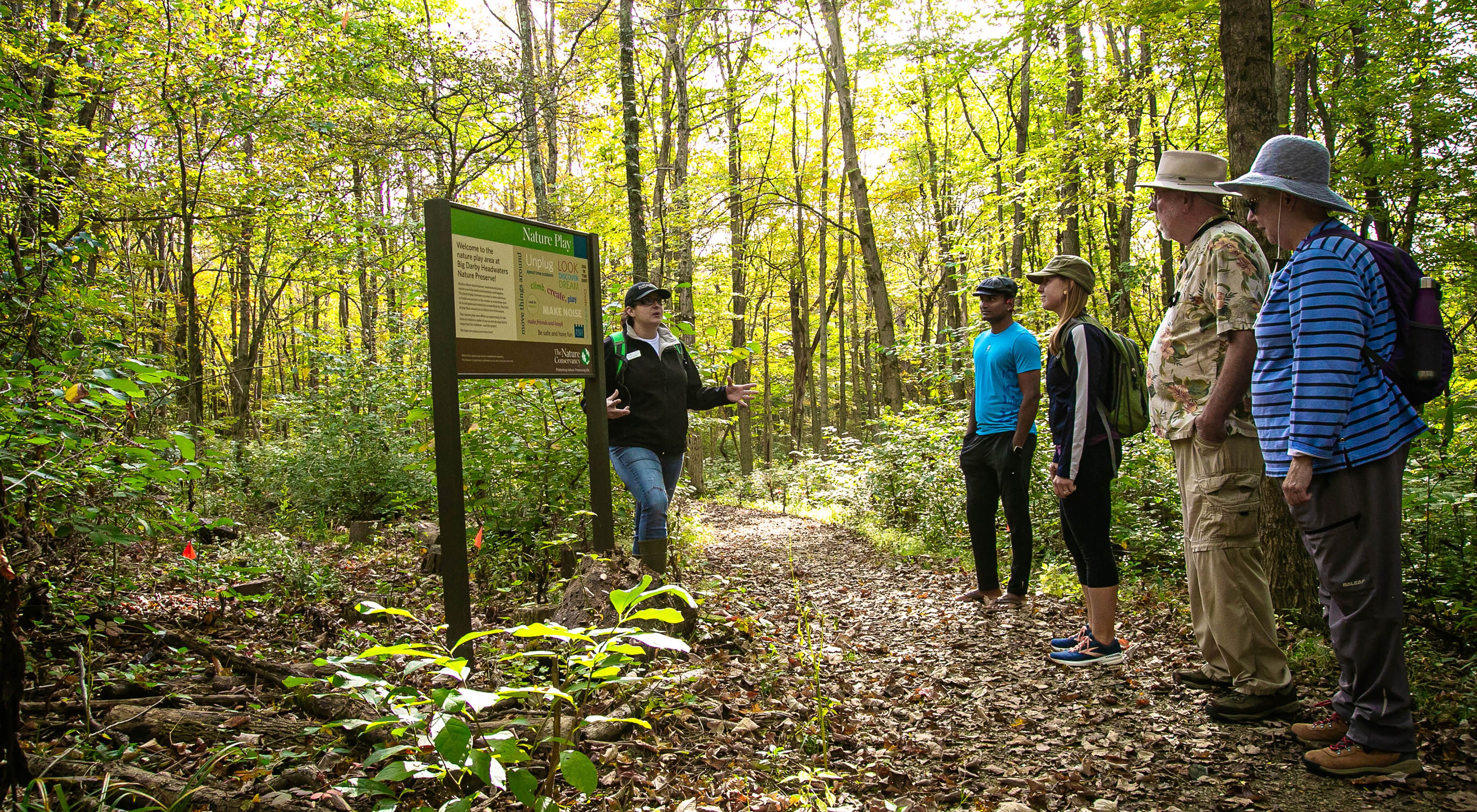 Community and Conservation Specialist Angie Burke talks to hikers in forest at Big Darby Headwaters Preserve.