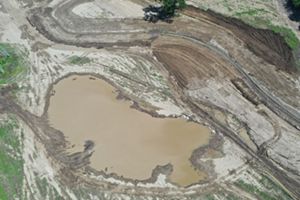 Aerial view of newly created wetland with surrounded by bare ground.