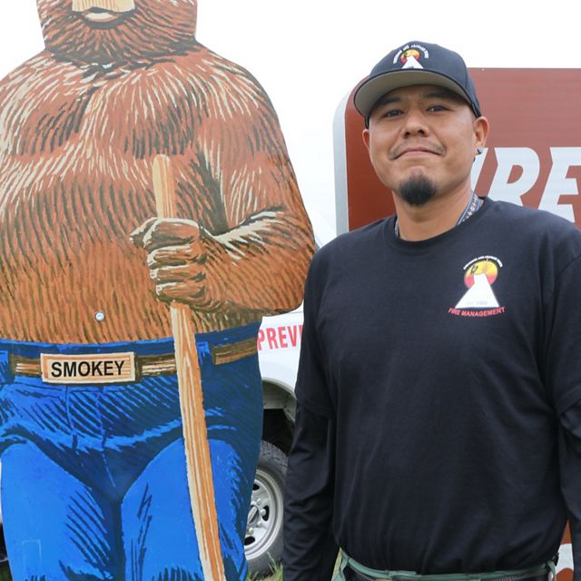 Man standing next to Smokey Bear.