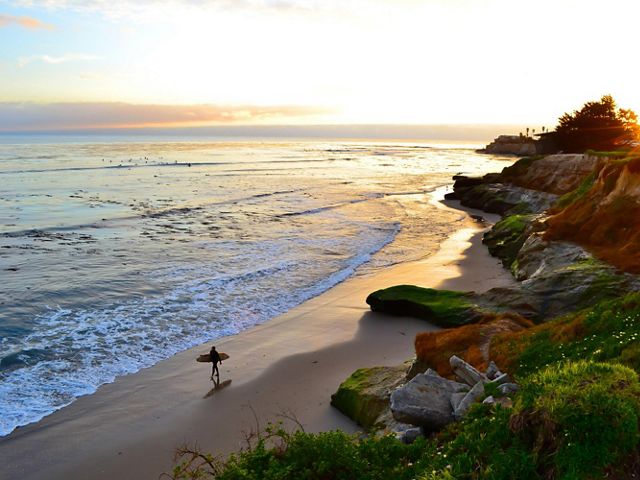 Surfer walking along the beach in Santa Cruz.
