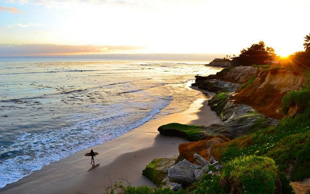 Surfer walking along the beach in Santa Cruz.