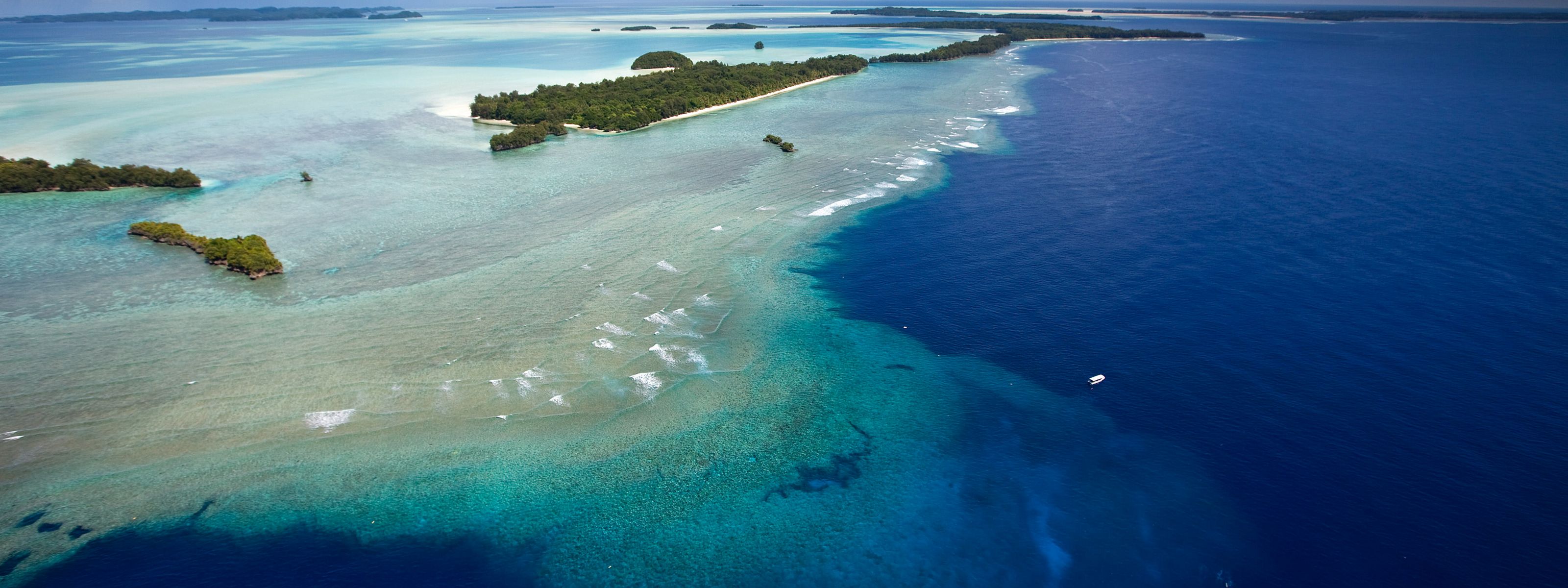 Aerial view of the sparkling blue waters of Palau, with a stretch of narrow islands.
