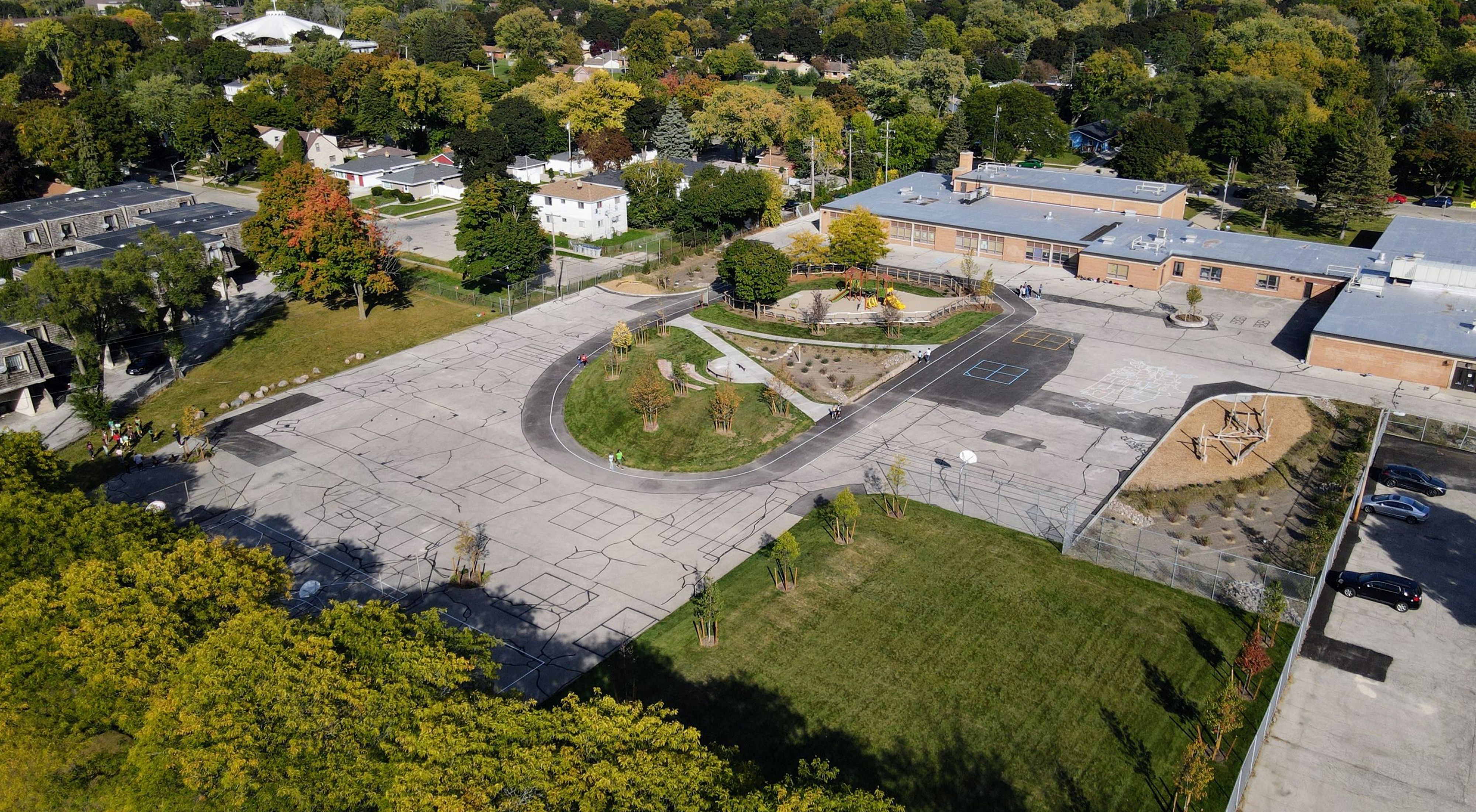 Aerial view of a schoolyard with grass and trees interspersed with playground equipment.