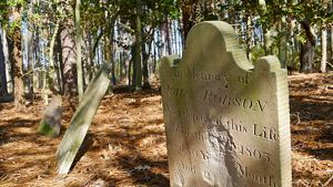 A row of headstones. The nearest marker reads, In memory of John Robson Who departed this Life May 1805 Aged 40 years. The center of the marker has eroded away. The stone next to it is tilted back.
