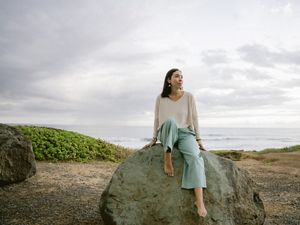 Portrait of Andrea Akall'eq Burgess sitting on a large boulder.