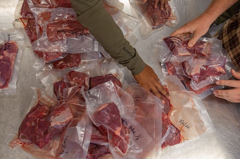 A close up image of several vacuum-sealed plastic bags containing raw meat. 