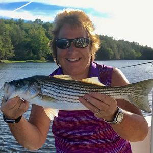 La bióloga Sandy Ritchie sonríe mientras muestra una lubina rayada que capturó en el río Kennebec.