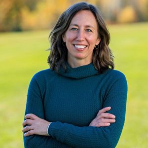 An image of Sarah Garlick, smiling with her arms folded.