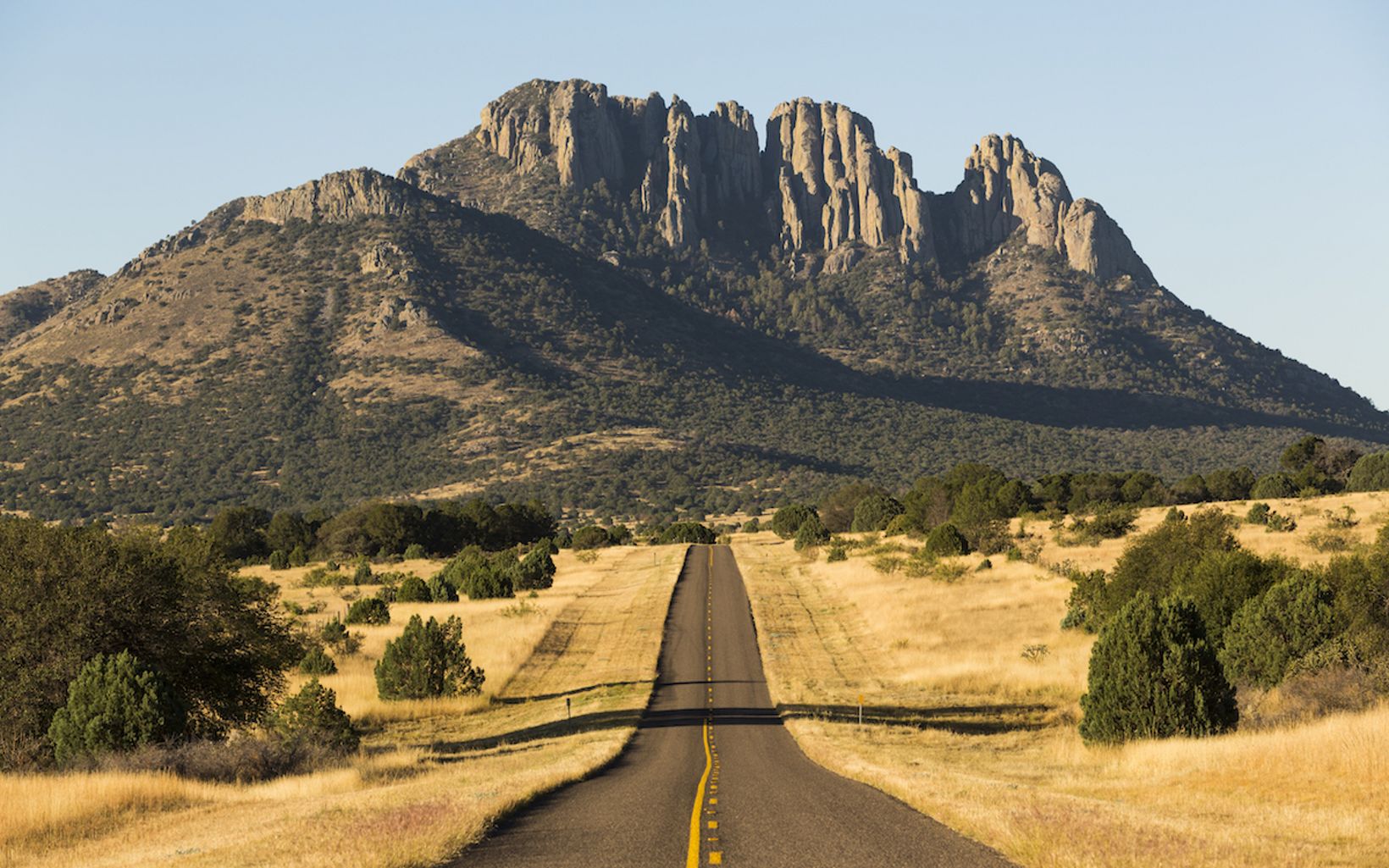 A road stretches in front of Sawtooth Mountain towering in the distance.