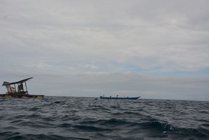 Water-level view of a small boat on the surface of a wide ocean.