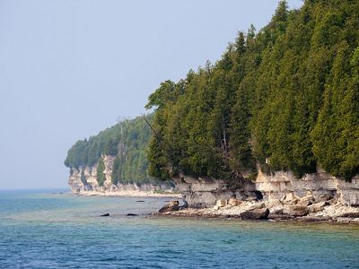 A rocky shoreline with conifer trees along Lake Michigan. 