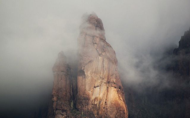 A towering mountain peeks through the foggy sky.