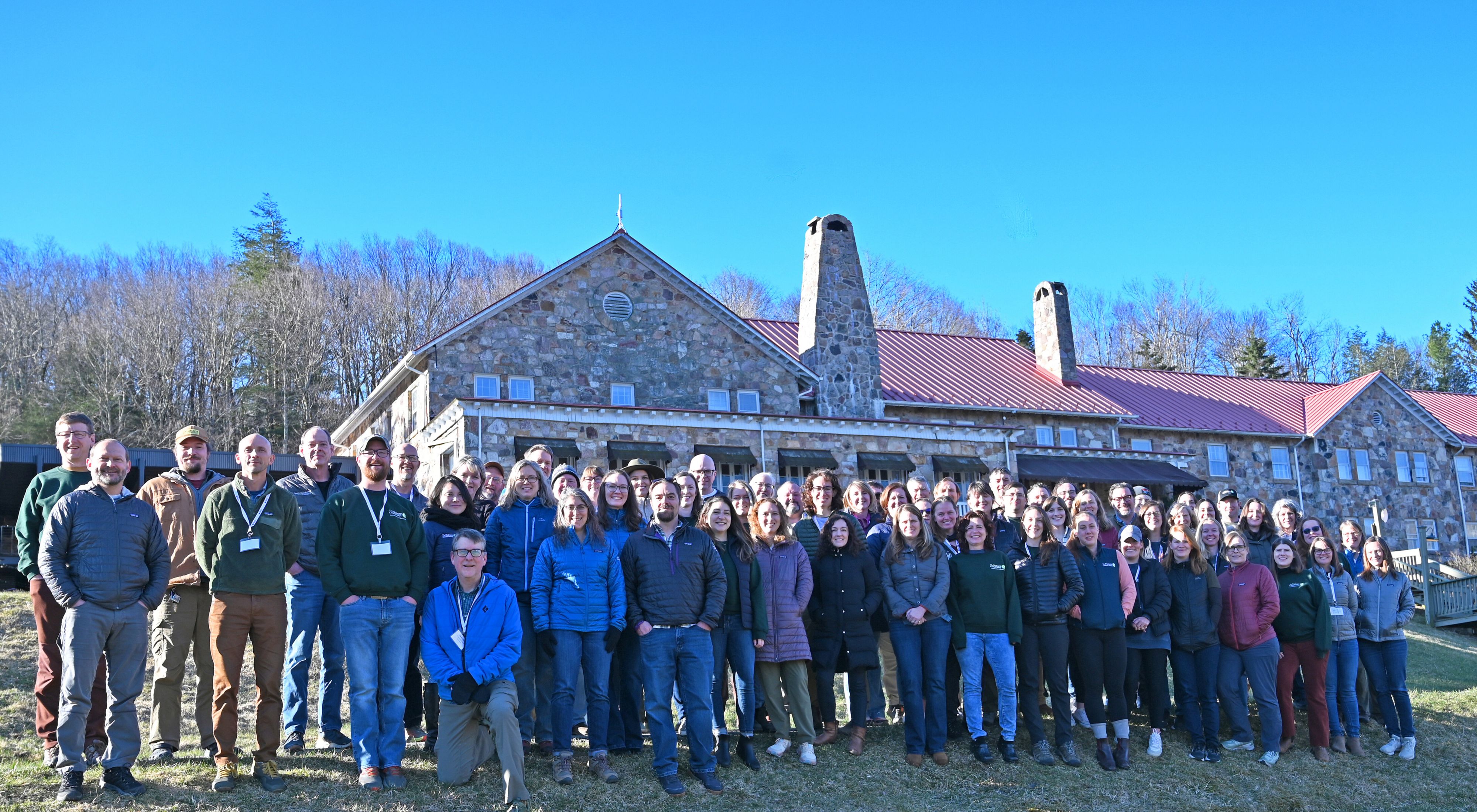 Group photo of TNC VA staff. A large group of people stand together outdoors in front of Mountain Lake Lodge during the chapter's annual staff retreat.