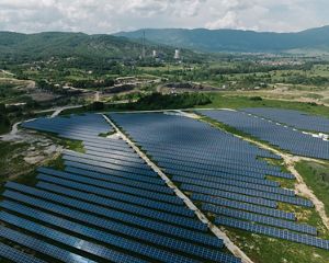 A vast expanse of solar panels in the foreground leads to the base of a now-defunct coal plant in North Macedonia.