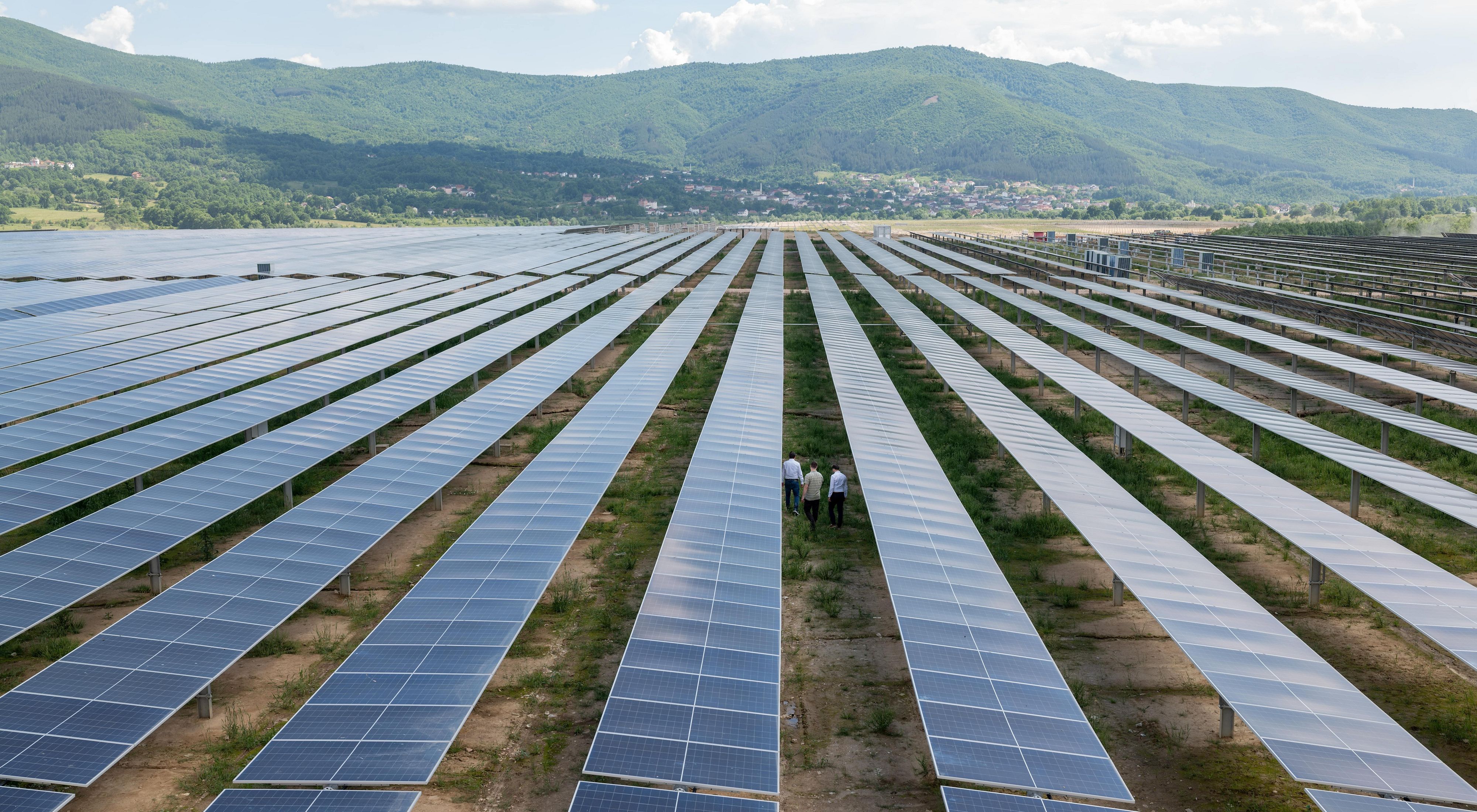 Aerial view of people walking among rows of solar panels.