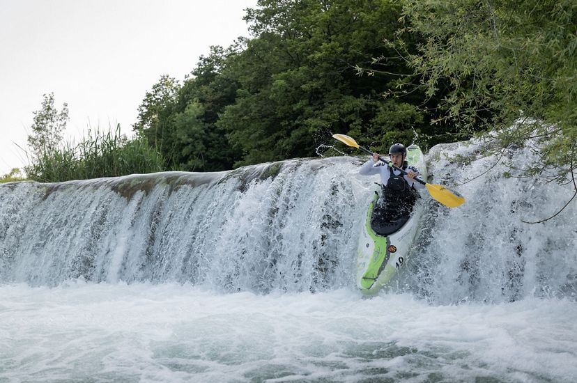A person in a kayak goes over the edge of a short waterfall.