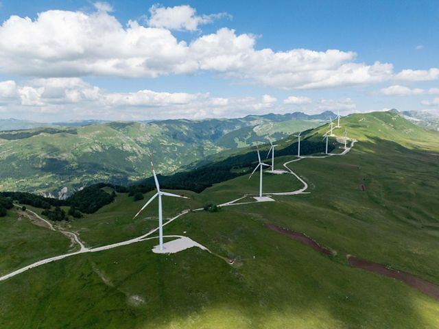 A row of wind turbines atop a mountain.