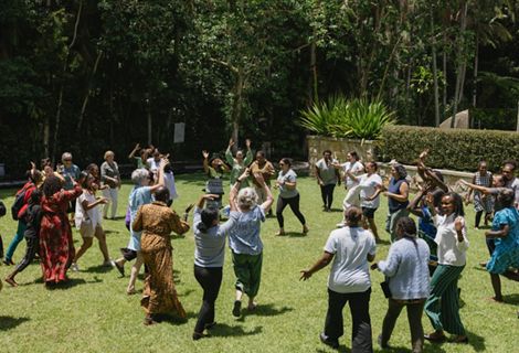 A group of people participate in an outdoor activity and run across grass.
