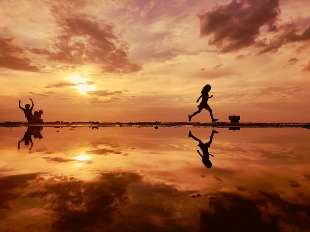 Children run along the low tide's shallow waters, their image reflected in the waters off Cagayan de Oro City, Philippines.