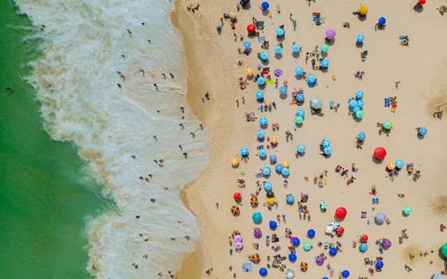 aerial view of beachgoers with colorful umbrellas on a beach on the ocean