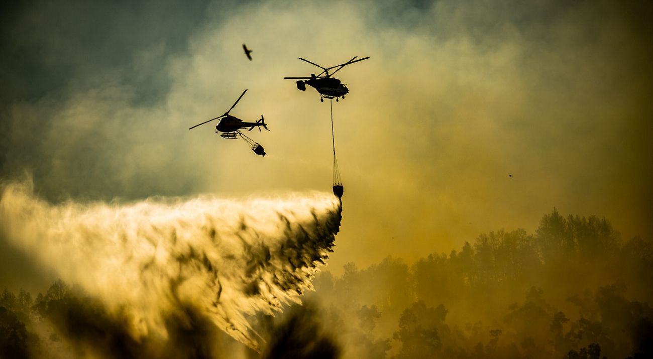 Helicopters prepare to drop water on a wildfire in Spain in 2023.